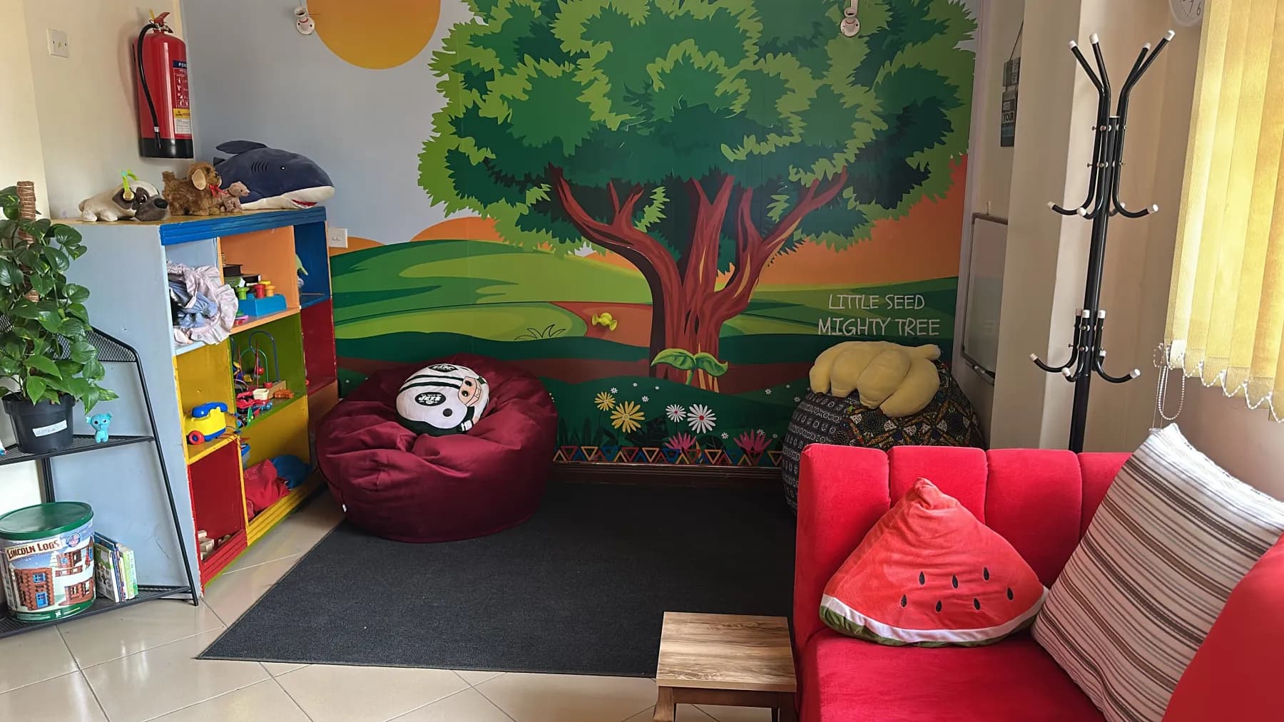 Blossom children's playroom with a tree mural reading Little Seed, Mighty Tree, bean bags and toy shelves
